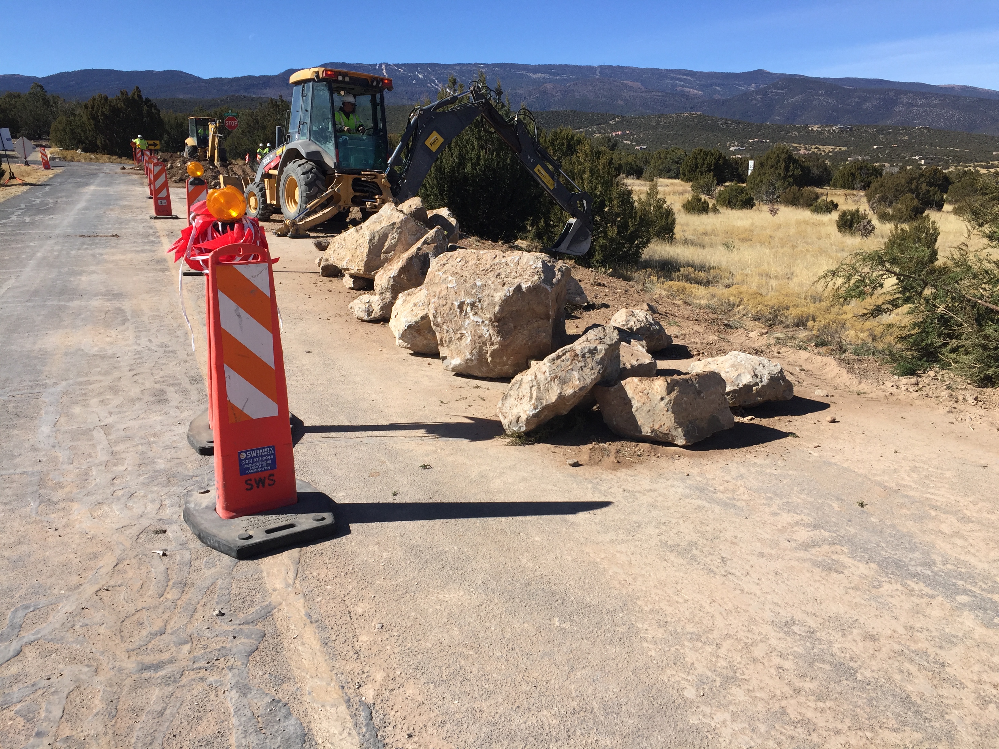 Backhoes and large rocks on the side of a safely guarded highway.